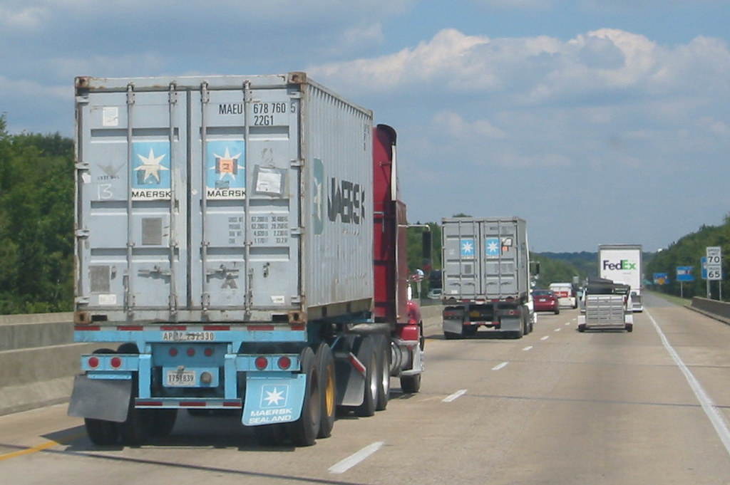 Highway freight corridor with trucks passing under bridge infrastructure